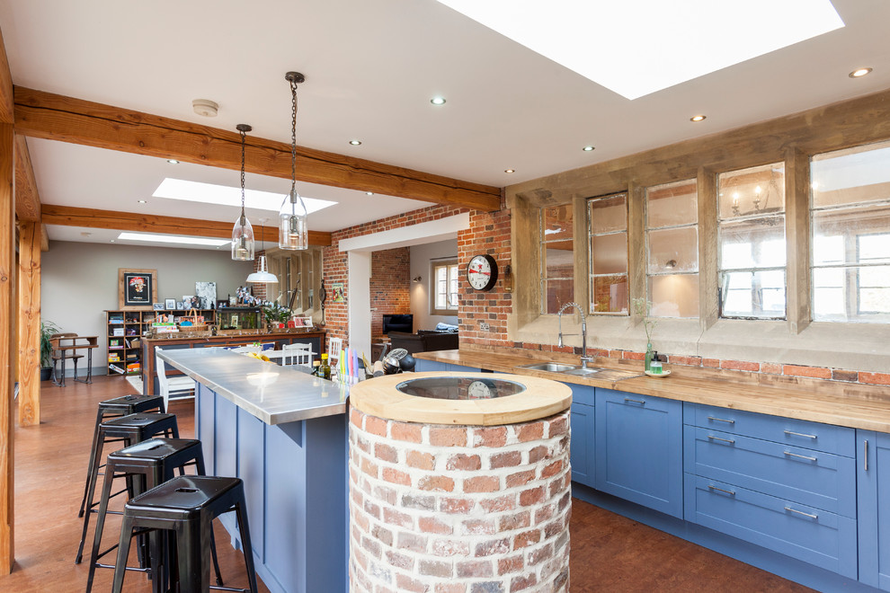 Пример оригинального дизайна: кухня в стиле лофт с накладной мойкой, фасадами с утопленной филенкой, синими фасадами, деревянной столешницей и островом