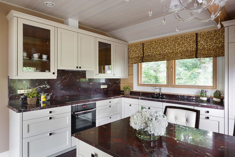Diseño de cocina tradicional renovada con armarios con paneles empotrados, puertas de armario blancas, electrodomésticos negros y una isla