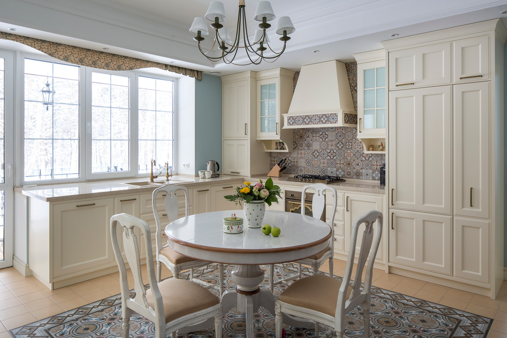 Источник вдохновения для домашнего уюта: угловая кухня в классическом стиле с обеденным столом, накладной мойкой, фасадами с утопленной филенкой, бежевыми фасадами, разноцветным фартуком, цветной техникой и окном