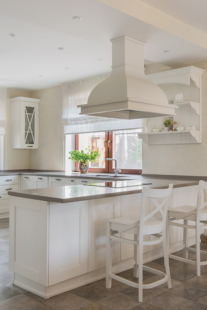 Пример оригинального дизайна: п-образная кухня в стиле неоклассика (современная классика) с обеденным столом, двойной мойкой, фасадами с утопленной филенкой, белыми фасадами, полуостровом, коричневым полом и серой столешницей в частном доме