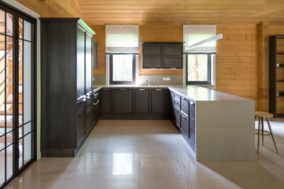 На фото: большая п-образная кухня-гостиная в современном стиле с фасадами с утопленной филенкой, столешницей из акрилового камня, полом из керамогранита, полуостровом, черными фасадами и серым фартуком
