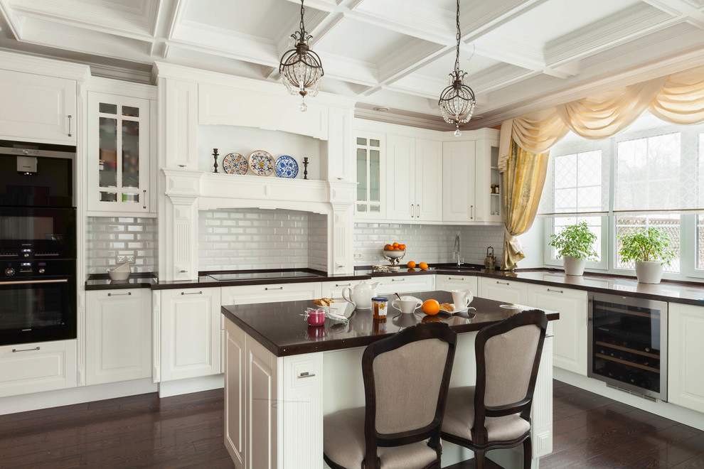 Immagine di una cucina classica con lavello da incasso, ante bianche, paraspruzzi bianco, paraspruzzi con piastrelle diamantate, elettrodomestici neri e pavimento marrone