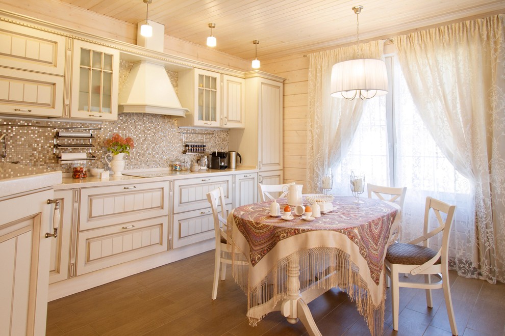 На фото: кухня в классическом стиле с обеденным столом, белыми фасадами, бежевым фартуком и фартуком из плитки мозаики в частном доме