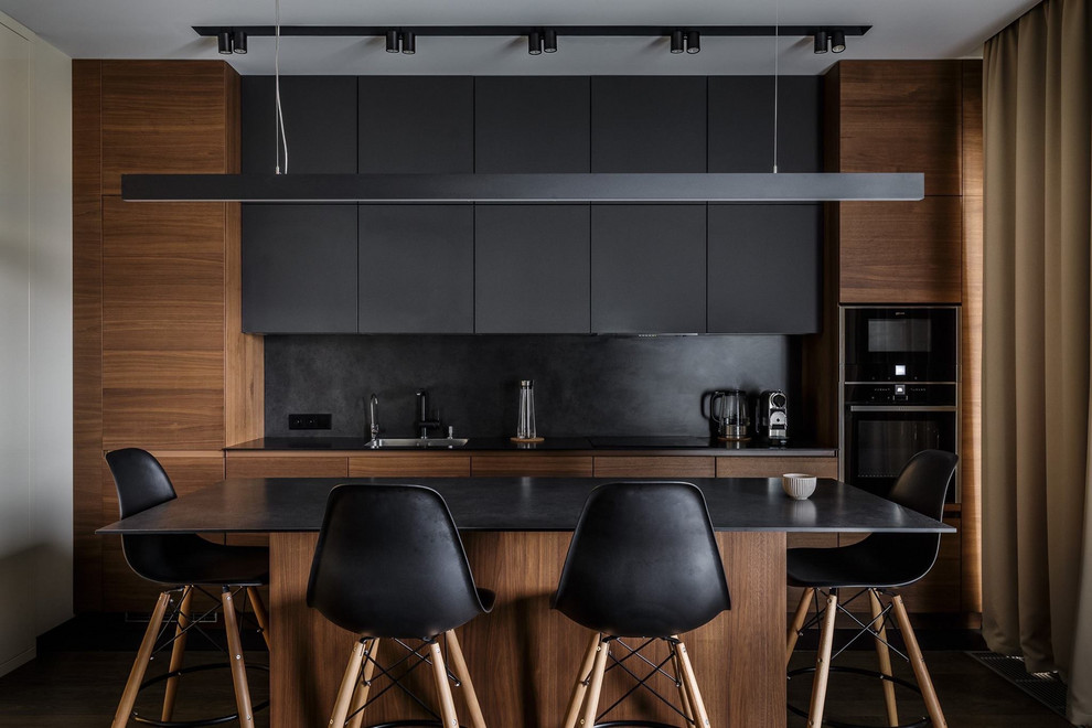 Bild på ett mellanstort funkis svart svart kök, med en undermonterad diskho, släta luckor, en köksö, svart stänkskydd, stänkskydd i sten, svarta vitvaror och svarta skåp