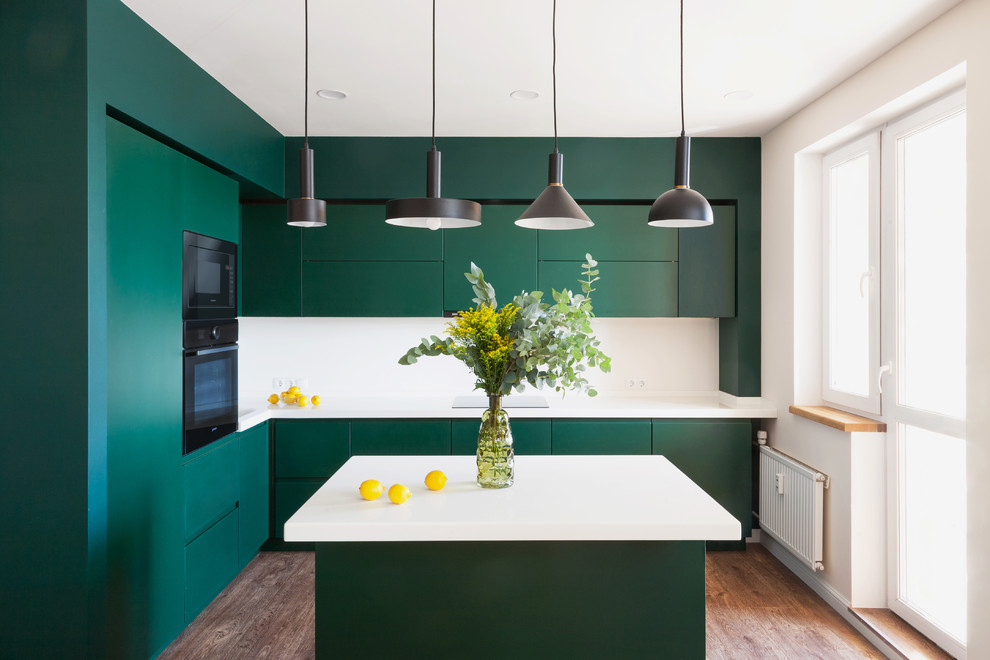 Design ideas for a contemporary l-shaped kitchen in Moscow with a submerged sink, flat-panel cabinets, green cabinets, white splashback, black appliances, medium hardwood flooring, an island and white worktops.