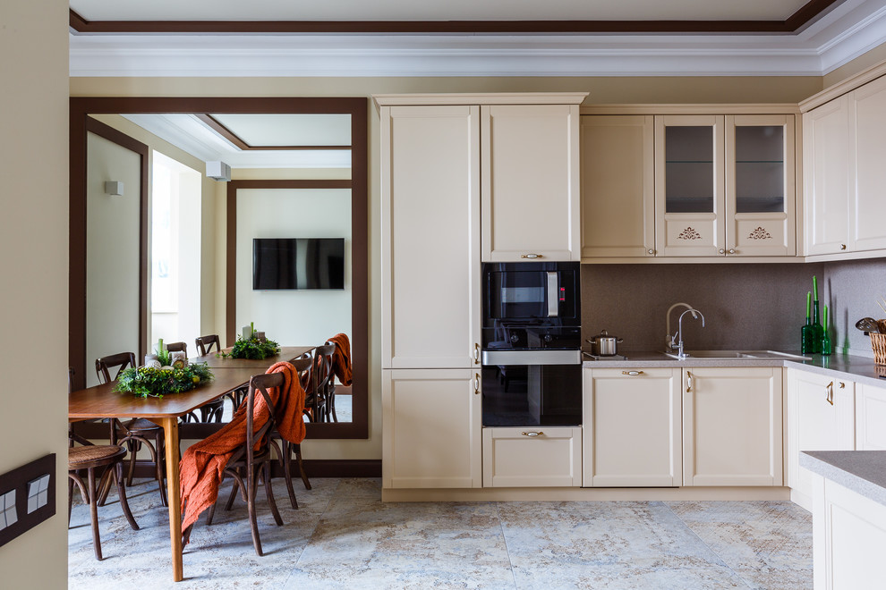 Идея дизайна: п-образная кухня-гостиная в стиле неоклассика (современная классика) с накладной мойкой, фасадами в стиле шейкер, бежевыми фасадами, серым фартуком, черной техникой и полуостровом