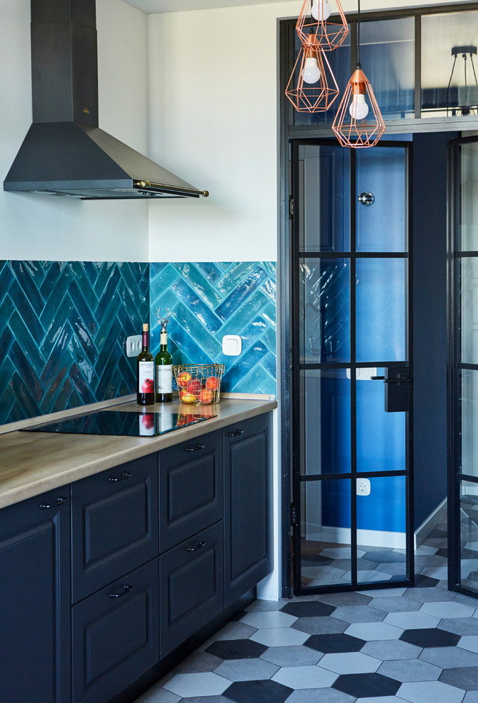 Modern inredning av ett beige linjärt beige kök, med luckor med upphöjd panel, svarta skåp, blått stänkskydd, grått golv, träbänkskiva, stänkskydd i keramik och cementgolv