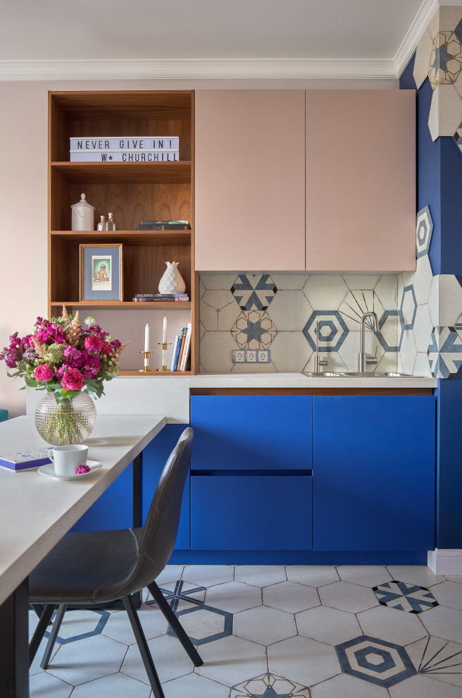 На фото: маленькая угловая кухня в современном стиле с обеденным столом, накладной мойкой, плоскими фасадами, синими фасадами, разноцветным фартуком, разноцветным полом и серой столешницей для на участке и в саду