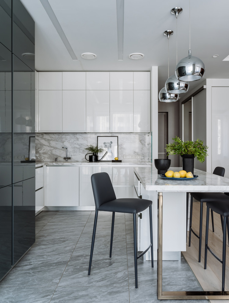 Стильный дизайн: угловая кухня в современном стиле с плоскими фасадами, белым фартуком, островом, серым полом, белой столешницей и черно-белыми фасадами - последний тренд