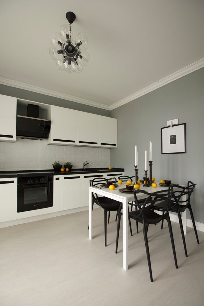 Источник вдохновения для домашнего уюта: прямая кухня в современном стиле с плоскими фасадами, белым фартуком, черной техникой и черно-белыми фасадами без острова