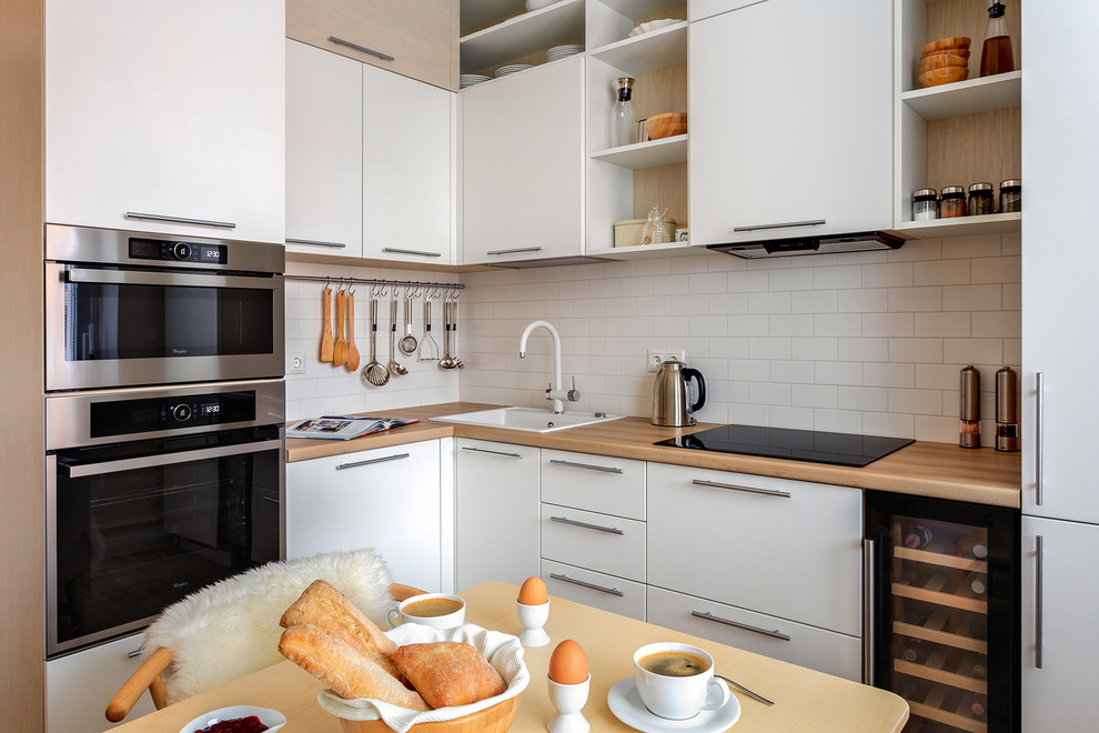 モスクワにあるお手頃価格の小さな北欧スタイルのおしゃれなキッチン (ドロップインシンク、フラットパネル扉のキャビネット、白いキャビネット、ラミネートカウンター、白いキッチンパネル、シルバーの調理設備、アイランドなし、磁器タイルのキッチンパネル) の写真