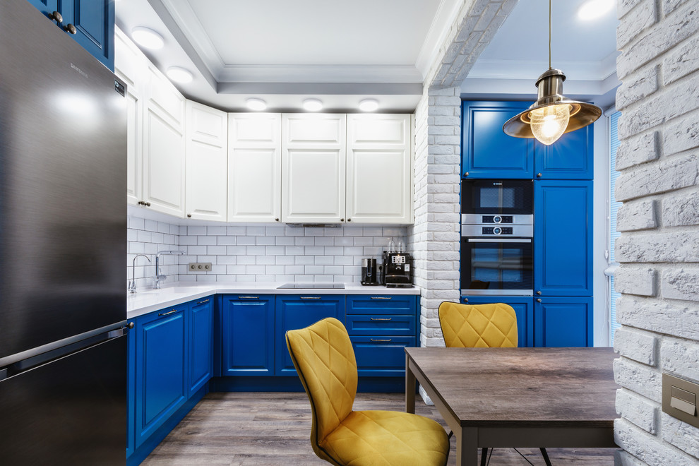 Design ideas for a medium sized industrial l-shaped kitchen/diner in Moscow with an integrated sink, raised-panel cabinets, blue cabinets, composite countertops, white splashback, ceramic splashback, stainless steel appliances, laminate floors, no island, brown floors and white worktops.