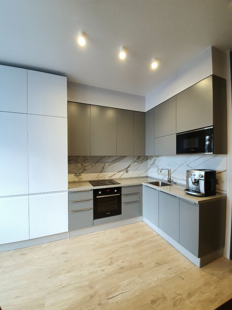Idée de décoration pour une cuisine ouverte minimaliste en L de taille moyenne avec un placard à porte plane, des portes de placard grises et un plan de travail en surface solide.
