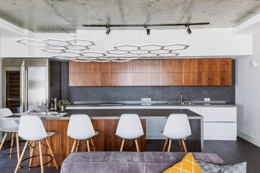 Inspiration for an urban open plan kitchen in Novosibirsk with flat-panel cabinets, medium wood cabinets, grey splashback, an island, grey floors, an integrated sink, stainless steel worktops, stainless steel appliances and concrete flooring.
