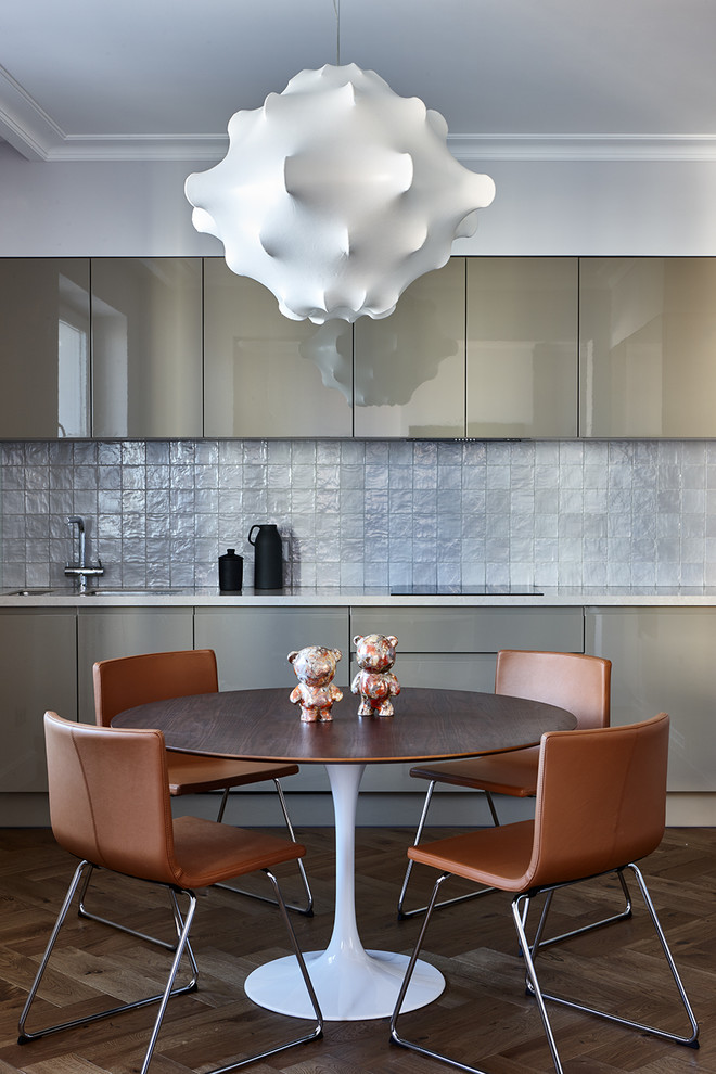 Immagine di una cucina contemporanea con ante lisce, paraspruzzi grigio e pavimento marrone