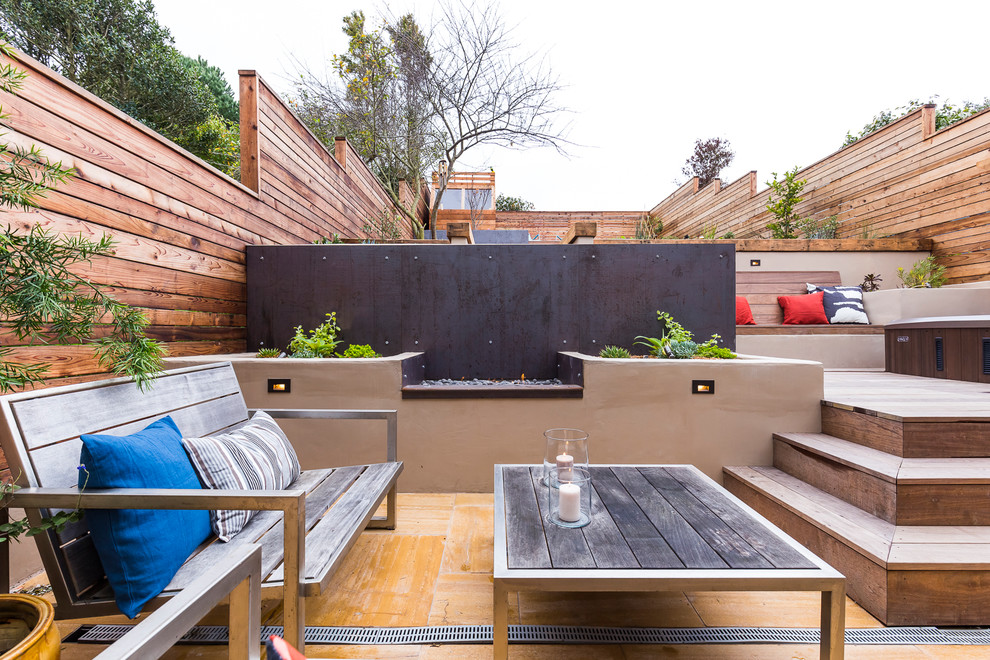 This is an example of a large contemporary back full sun garden in San Francisco with a retaining wall and decking.