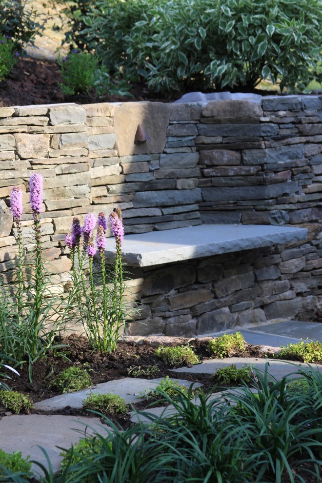 Immagine di un grande giardino country esposto in pieno sole dietro casa in estate con un muro di contenimento e pavimentazioni in pietra naturale