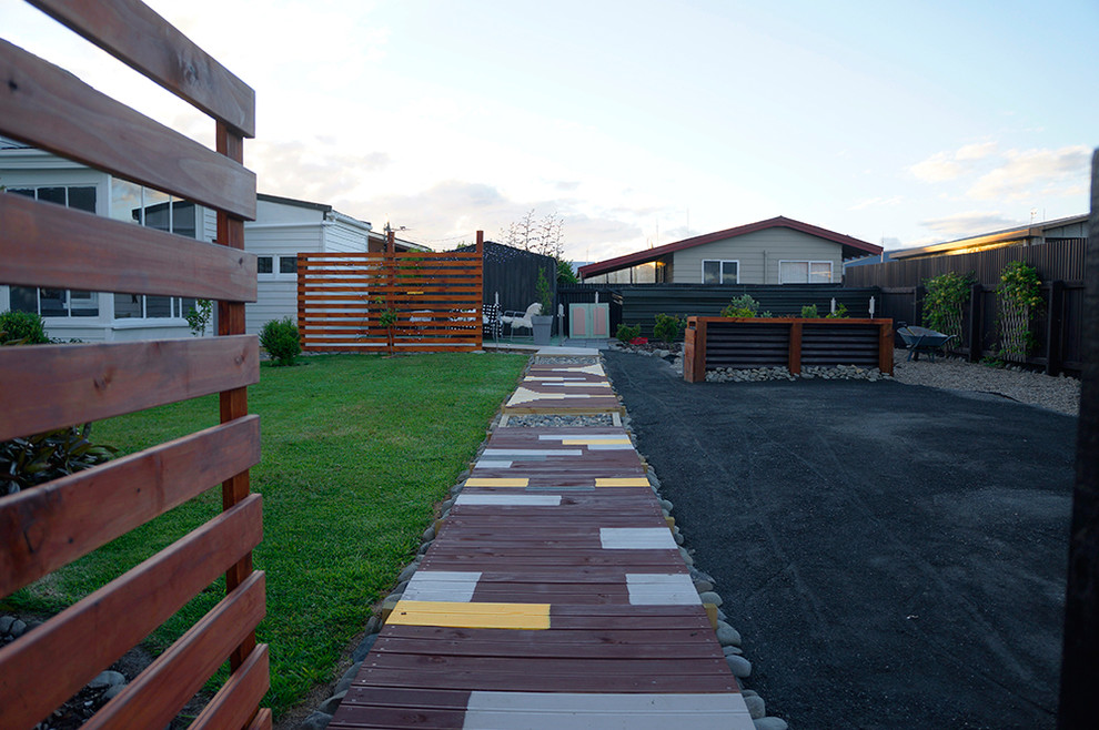 Réalisation d'une allée carrossable arrière bohème avec une terrasse en bois.