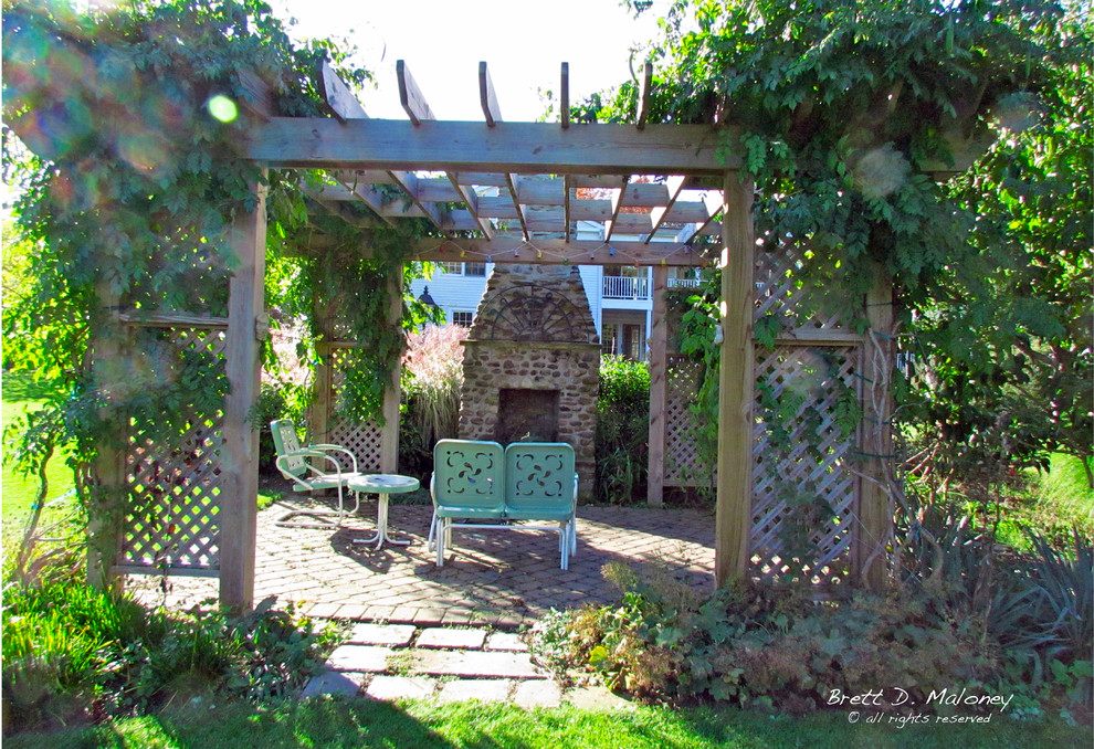 Réalisation d'un grand jardin arrière champêtre l'été avec une exposition ensoleillée et des pavés en béton.