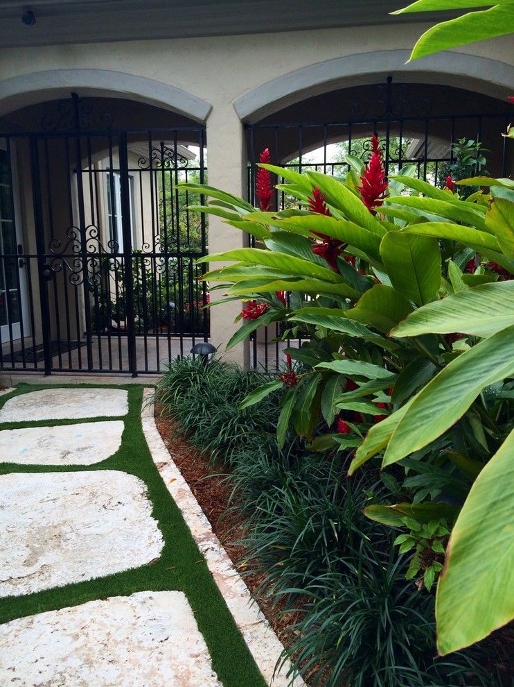 Immagine di un grande giardino tropicale esposto a mezz'ombra nel cortile laterale in estate con un ingresso o sentiero e pavimentazioni in pietra naturale