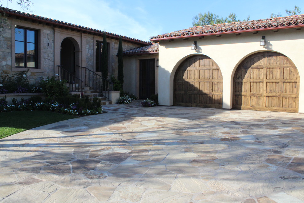 This is an example of a mediterranean front driveway garden in Orange County with a garden path and natural stone paving.