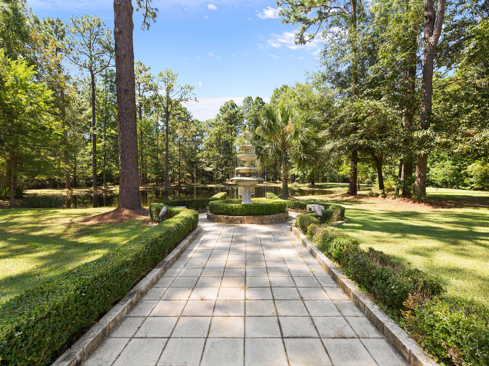 Inspiration for a classic front garden in New Orleans with a pond and concrete paving.