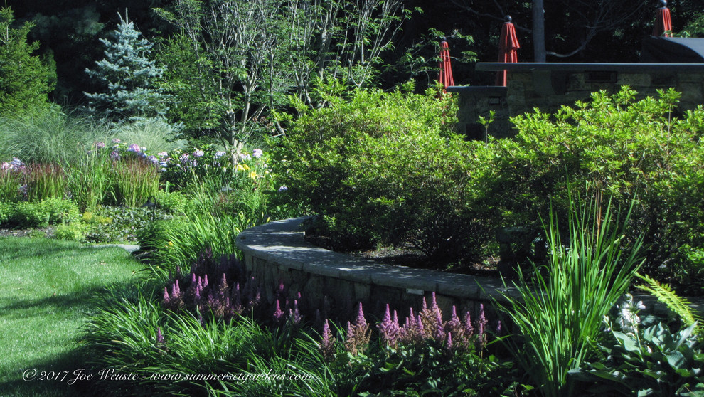 Cette image montre un jardin arrière traditionnel de taille moyenne avec un mur de soutènement et une exposition partiellement ombragée.