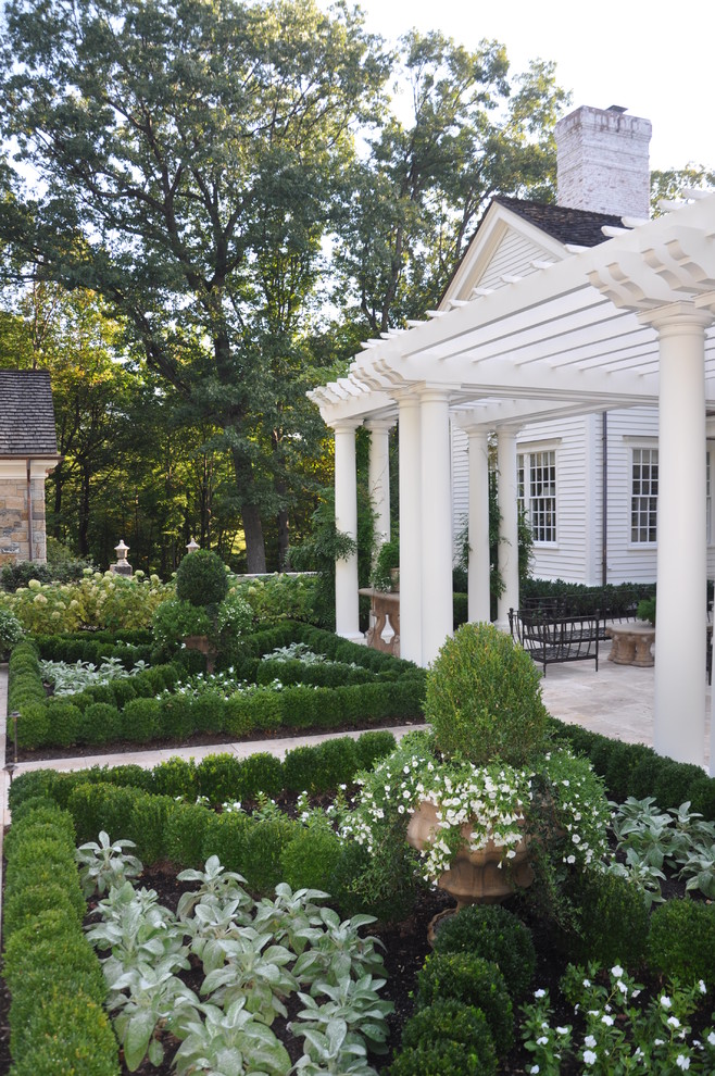 Inspiration for a small french country backyard stone formal garden in New York with a pergola.