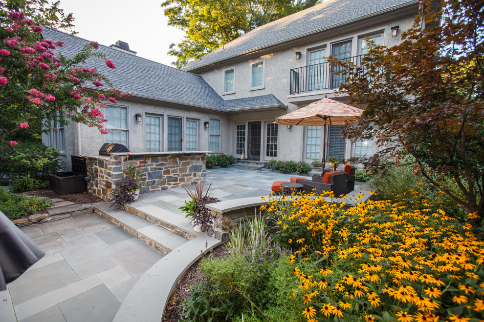 Стильный дизайн: большой летний участок и сад на переднем дворе с клумбами, полуденной тенью и покрытием из каменной брусчатки - последний тренд