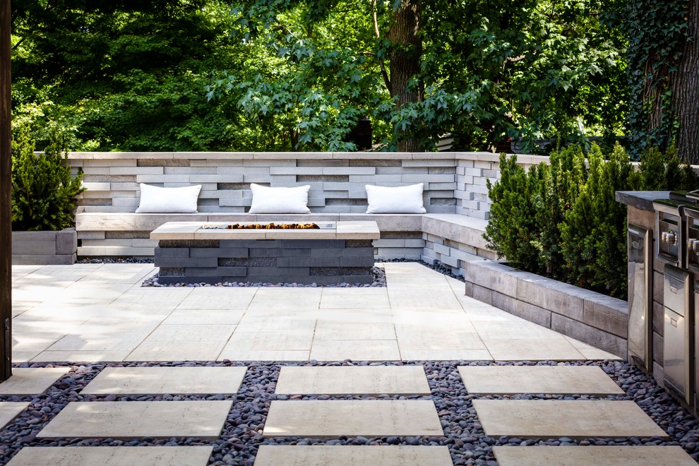 Idée de décoration pour une terrasse arrière design de taille moyenne avec un foyer extérieur et des pavés en pierre naturelle.