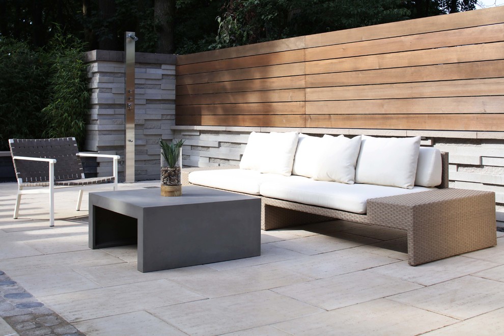 Réalisation d'une terrasse arrière design de taille moyenne avec un foyer extérieur et des pavés en pierre naturelle.