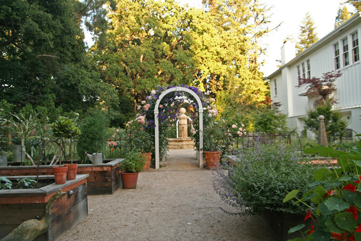 Immagine di un ampio giardino formale classico esposto in pieno sole nel cortile laterale in primavera con ghiaia e fontane