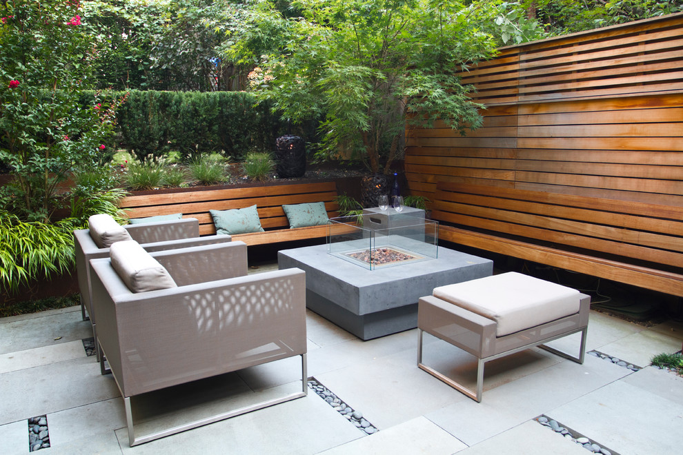 Photo of a modern back patio in New York with a fire feature and concrete paving.