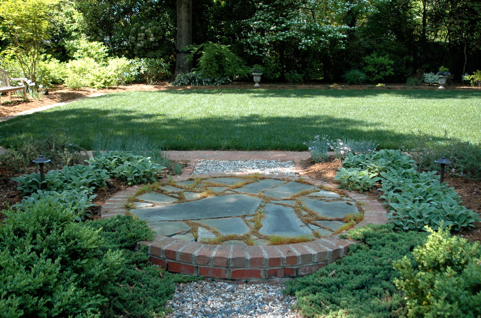 Ejemplo de jardín clásico de tamaño medio en verano en patio trasero con adoquines de piedra natural y jardín francés