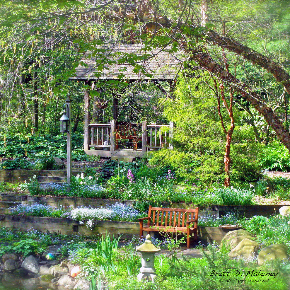 Foto di un grande giardino american style esposto a mezz'ombra dietro casa in estate con pavimentazioni in pietra naturale e un muro di contenimento