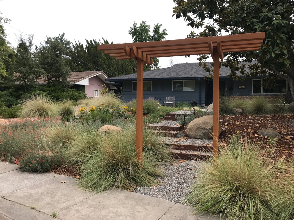 Inspiration for a medium sized midcentury front xeriscape full sun garden in Other with a garden path, gravel and a wood fence.