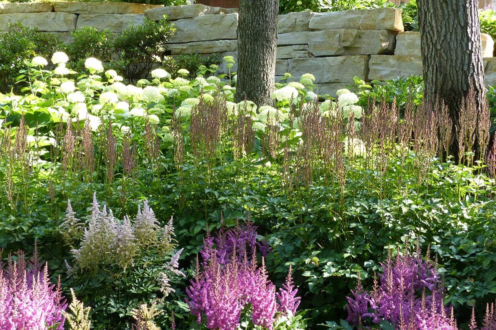 На фото: большой летний засухоустойчивый сад на заднем дворе в стиле кантри с подпорной стенкой, полуденной тенью и покрытием из каменной брусчатки с