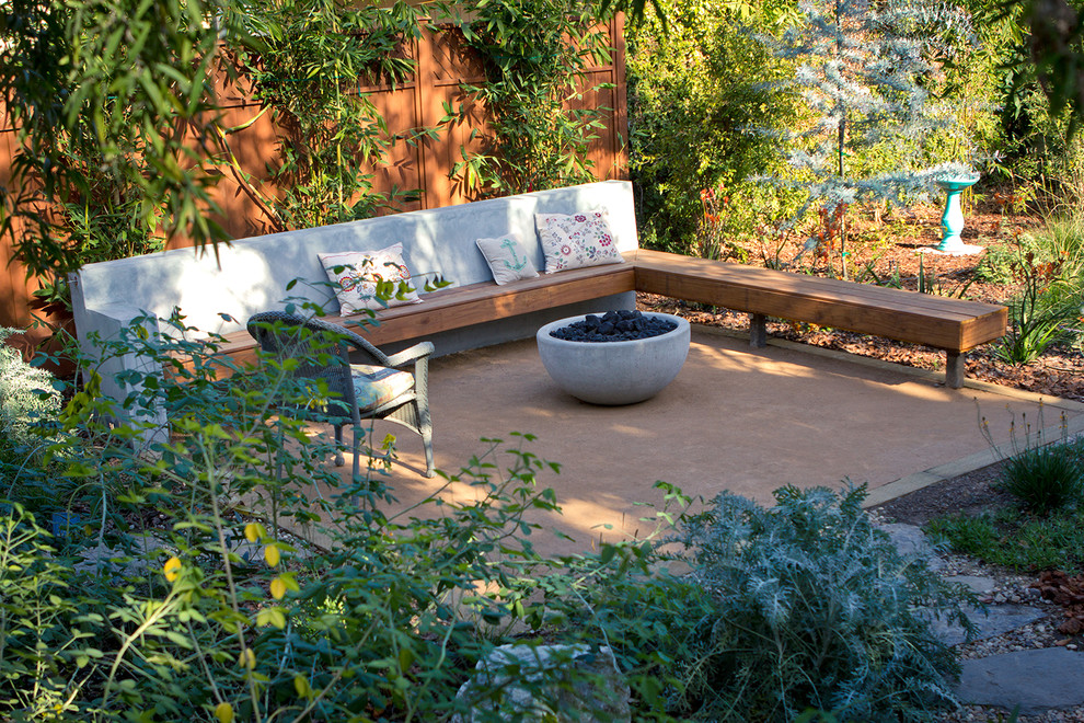 This is an example of a mid-sized mediterranean drought-tolerant backyard stone landscaping in Los Angeles with a fire pit.