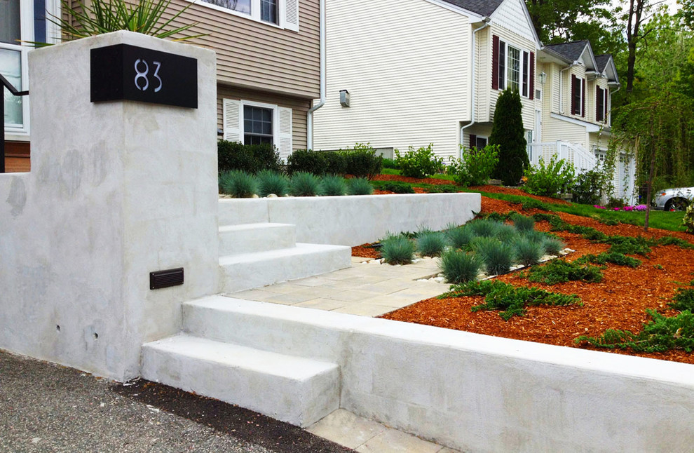 Medium sized contemporary front driveway partial sun garden for winter in Providence with concrete paving and a retaining wall.