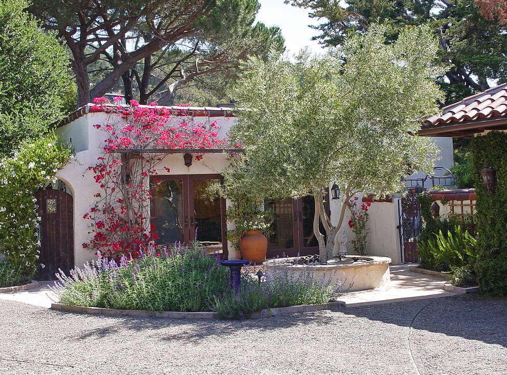 На фото: большой летний засухоустойчивый сад на внутреннем дворе в средиземноморском стиле с покрытием из гравия с