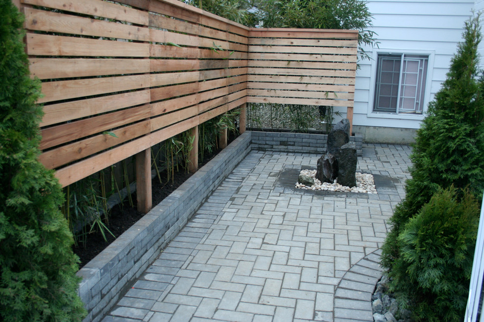 This is an example of a mid-sized asian shade backyard brick water fountain landscape in Vancouver.