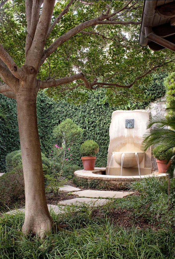 Ejemplo de jardín mediterráneo con adoquines de piedra natural y fuente