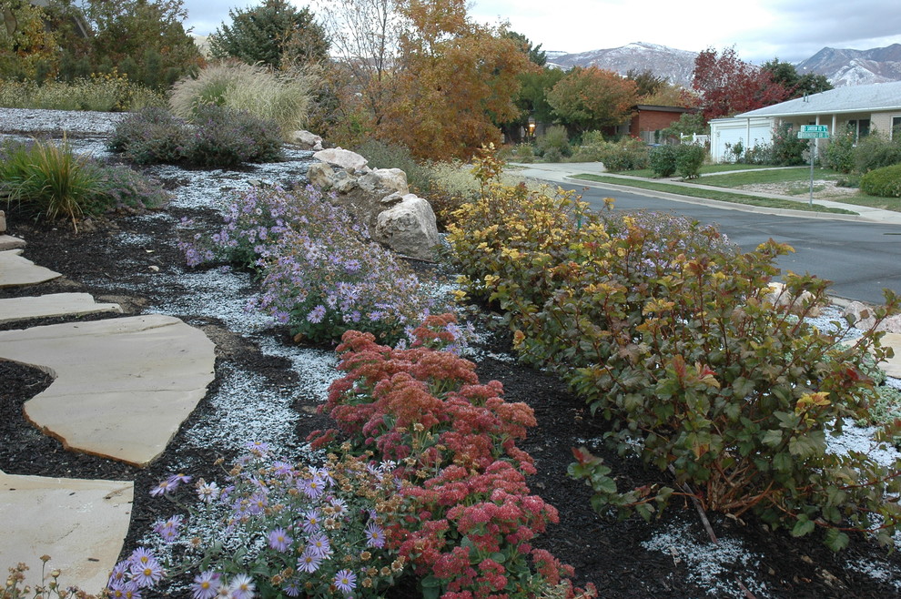 Exempel på en stor klassisk formell trädgård i delvis sol längs med huset på hösten, med naturstensplattor och en trädgårdsgång