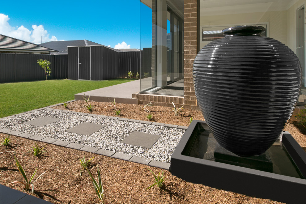 Diseño de jardín actual grande en patio trasero con fuente, exposición parcial al sol y mantillo