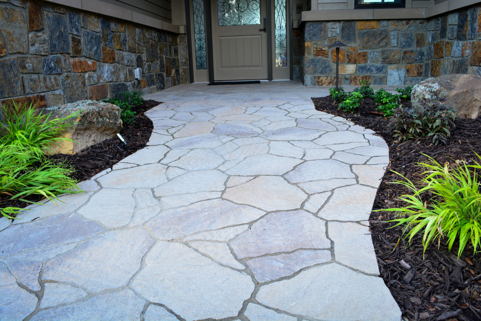 This is an example of a large rustic front partial sun garden in Omaha with natural stone paving.