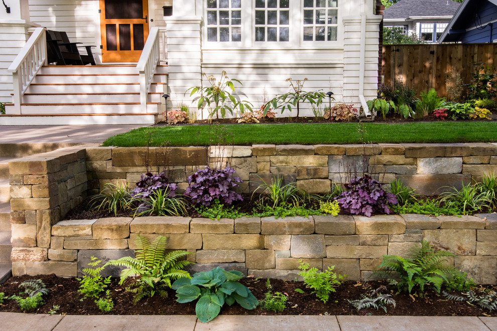 Ejemplo de jardín de estilo americano en patio delantero con muro de contención y adoquines de piedra natural