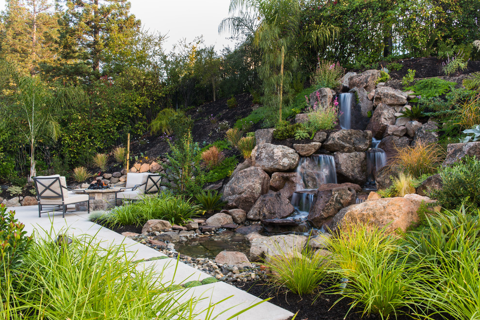 This is an example of a traditional sloped formal garden in San Francisco with a water feature and concrete paving.