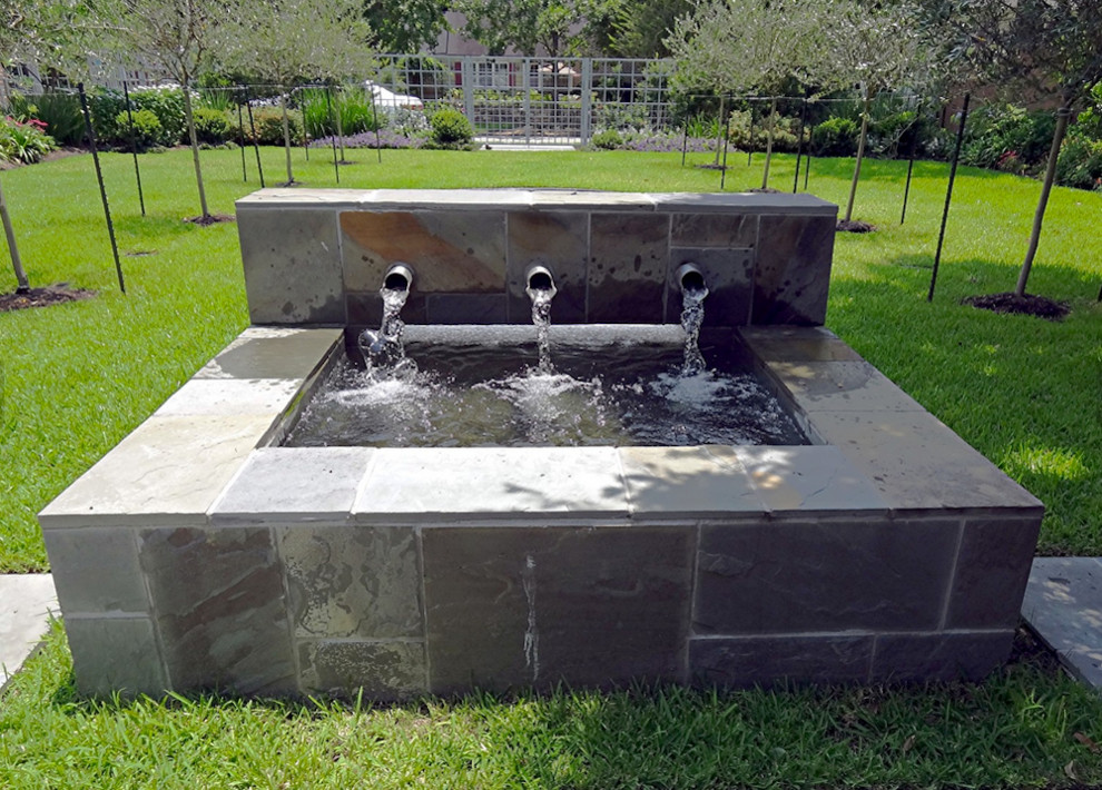 This is an example of a large traditional courtyard formal full sun raised pond for spring in Houston with a water feature and concrete paving.