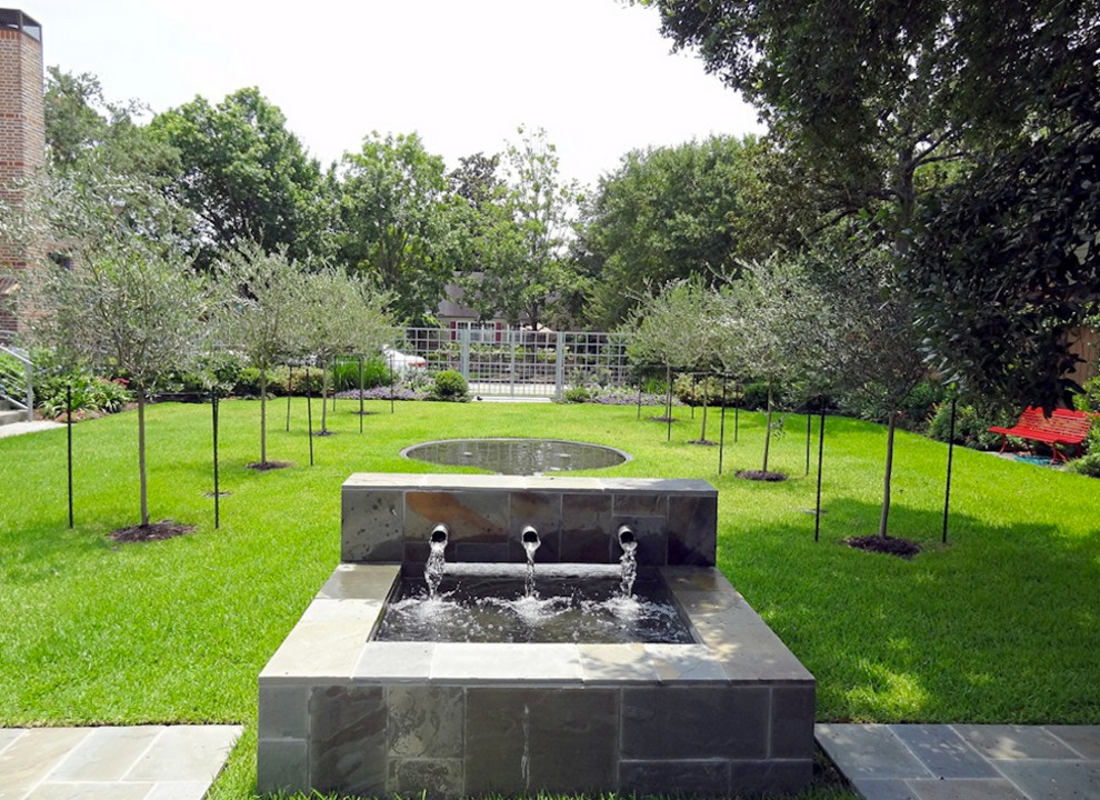 Photo of a large contemporary courtyard formal full sun garden for spring in Houston with a water feature and concrete paving.