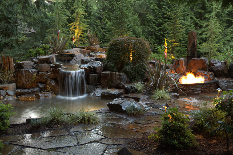 Réalisation d'un grand jardin arrière design avec un point d'eau, une exposition ensoleillée et des pavés en pierre naturelle.